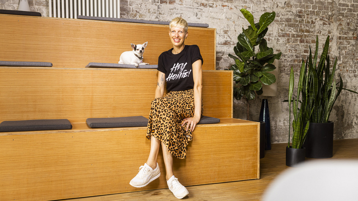 Recruiterin Nicole Janssen mit ihrem Hund auf einer Treppe im Hamburger Studio