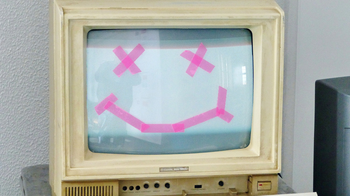 Alter Computerbildschirm mit aufgeklebtem Smiley-Motiv